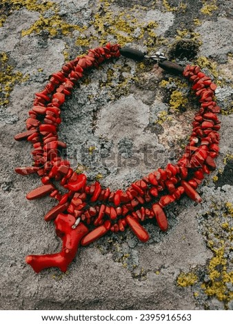 Red wide coral necklace Ukrainian traditional jewelry style Red triple necklace with pendant at white background Irregular beaded jewellery, female accessory Culture of Ukraine Stone background 

 Royalty-Free Stock Photo #2395916563