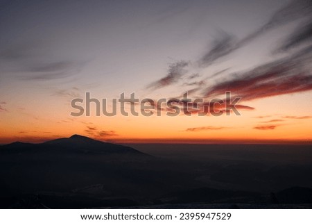 Fascinating colors of colorful winter sunset sky over distant silhouetted mountains. Shot can be used as a wallpaper or advertisement banner