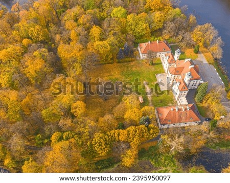 Aaerial view on the beautiful palace in Autumn sunset. White palace in the autumn forest. High altitude.