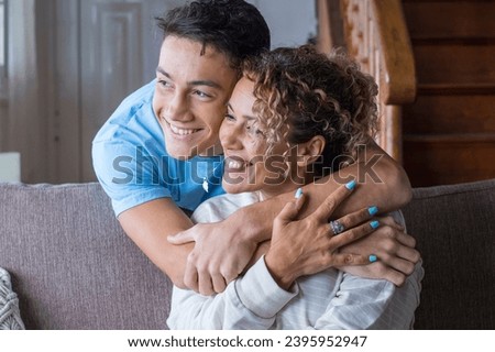 Happy middle age mother spend time with teenager son, relatives people hugging at home, adult attentive millennial grateful child wrapped in a plaid or warm sweater loving mommy caring about comfort Royalty-Free Stock Photo #2395952947