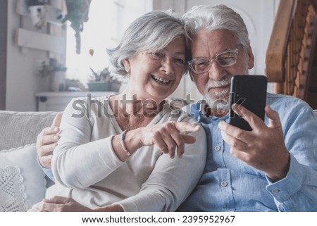 Smiling sincere mature older married family couple holding mobile video call conversation with friends, enjoying distant communication with grown children, using smartphone applications at home. Royalty-Free Stock Photo #2395952967