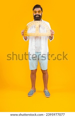smiling man hold geometry protractor isolated on yellow. man hold geometry protractor in studio.