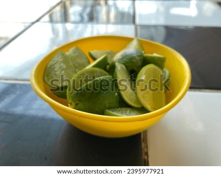 Bowl with fresh limes on black and white checkered table background