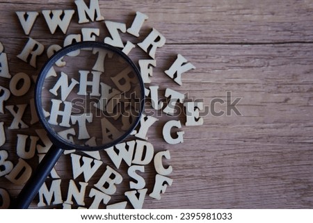 Magnifying glass with scattered alphabet letters on the table. Copy space for text. Education concept.
