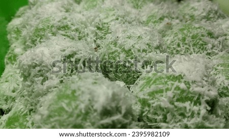 Closeup picture of Klepon,  is a snack of sweet rice cake balls filled with molten palm sugar and coated in grated coconut. The green color is made of the pandan leaf.