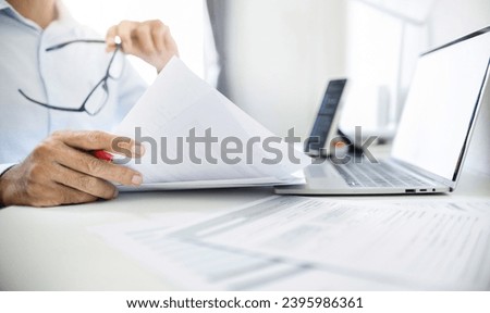 Close-up shot, business consultant holding pen reviewing documents and contact customer via laptop to give advice about business contracts and various important documents before investing in business
