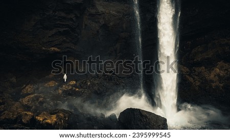 Female tourist walk on pathway visit famous Kvernufoos waterfall landmark. Yellow grass hills on Kvernufoss waterfall. Majestic summer view of pure water river in Iceland, Europe Royalty-Free Stock Photo #2395999545