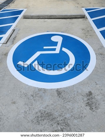 Blue rectangle handicapped sign with wheelchair. Handicapped symbol white on blue square frame and speed bump on a concrete road. To create convenience. Parking for wheelchair users slots are located 