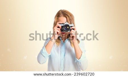 Blonde woman photographing over ocher background