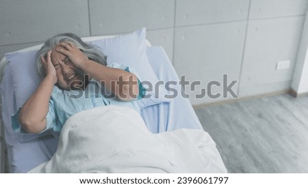 Asian elderly woman having migraine headaches on the bed in hospital 