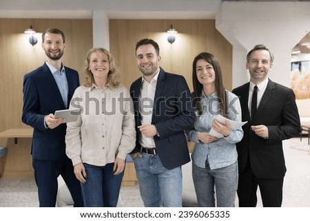Professionals, businesspeople, corporate staff members portrait. Five young and middle-aged employees posing standing in modern office smile look at camera. Business ambitions, company representatives Royalty-Free Stock Photo #2396065335