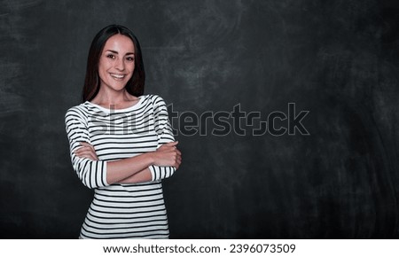 Close up photo of smiling cute happy young woman standing against blackboard in casual wear