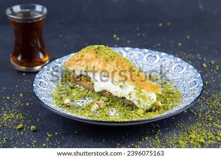Delicious Turkish baklava served with pistachio cream and cream ice cream on a plate. Turkish Ramadan Dessert Baklava kadayif with ice cream concept background Royalty-Free Stock Photo #2396075163
