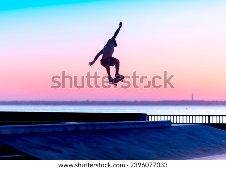 skateboarder silhouette jumping in a skatepark by the sea