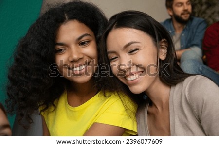 Close up photo of smiling multi ethnic girl friends sitting on the stairs in the school or college and have a fun together. Students in university after classes