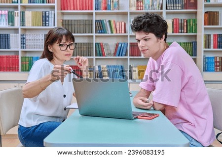 Woman mentor teaching male student in college library, exam preparation
