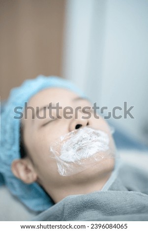 Esthetician applying numbing cream on patient's lips before injects filler.