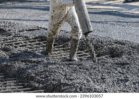 Construction worker is pouring and smoothing out concrete with ready-mix concrete (RMC). It is concrete that is manufactured in a batch plant, according to each specific job requirement. Royalty-Free Stock Photo #2396103057