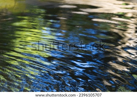 reflections in a calm water with green, yellow and different shades of blue for backgrounds Royalty-Free Stock Photo #2396105707