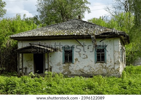 A house in a state of disrepair, with a collapsing roof and peeling paint, is captured in the photo. Royalty-Free Stock Photo #2396122089