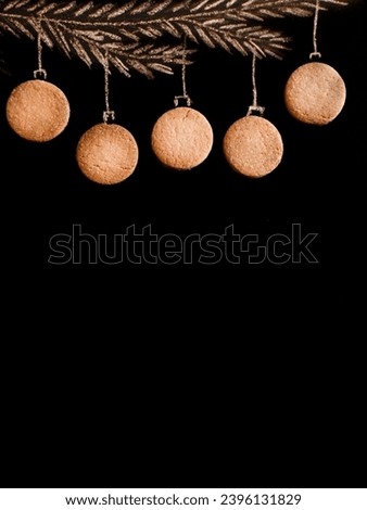 Drawing fir tree branch and Christmas macarons like new year balls hanging on Peach Fuzz trend 2024 color background. Merry christmas and happy new year, border with copy space, top view. Vertical.
