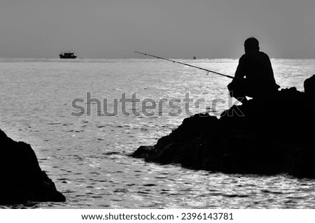beachside fishing on the rocks. Black and white photo.