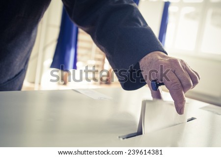 Hand of a person casting a ballot at a polling station during voting. Royalty-Free Stock Photo #239614381