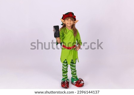 child girl in Santa's helper elf outfit with a cell phone with a blank screen with free space for text