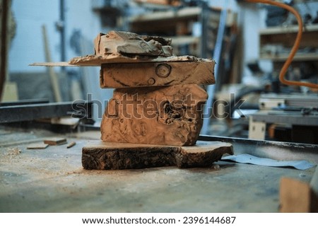 A captivating sculpture of wood burls piled atop one another awaits the creative touch of a woodworker in the midst of a sawdust-filled workshop. Royalty-Free Stock Photo #2396144687