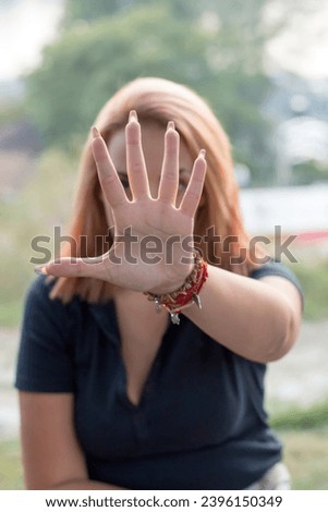 Please stop. Attractive young woman in park is displeased making a stop sign with her hand