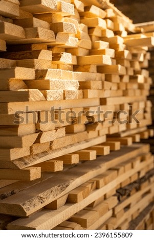 Stacked wooden planks in close-up at lumber warehouse. Air-drying timber stack. Wood air drying. Wood for house construction. Wood industry. Royalty-Free Stock Photo #2396155809