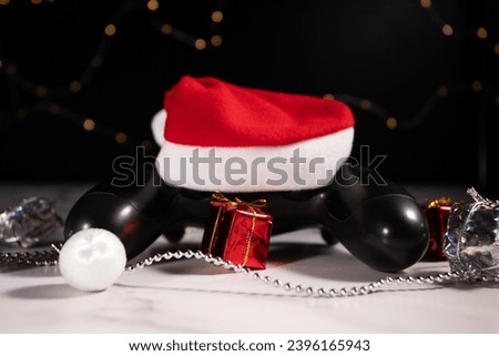 Game controller in Santa hat on Christmas background, a festive gaming device wrapped and ready for the holiday. The perfect present for gamers