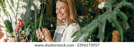 Woman florist writing orders and customer information in notebook at flower shop. High quality photo