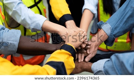 group of multiracial colleagues joining hands in morning meeting before going to work at a manufacturing industrial factory, teamwork of diverse worker stacking hands together motivate team building Royalty-Free Stock Photo #2396174365