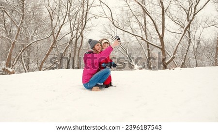 Mother and little toddler boy son having fun in the snow at winter. Winter holidays fun vacation sleigh riding concept.