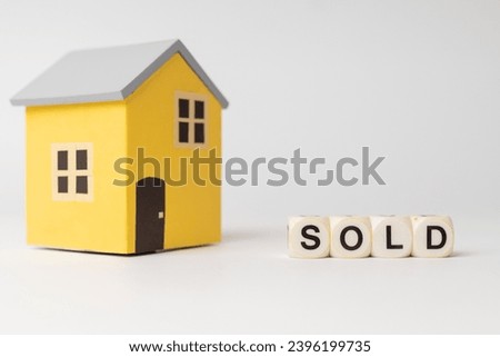 Close-up of House model with sold sign, isolated on white background