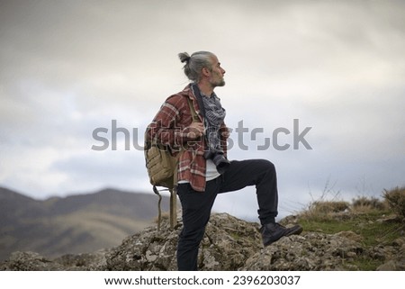 man walking around hills and foothills in autumn and taking photographs