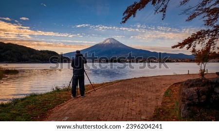 Rear view of Traveler man take photo Fuji mountain and kawaguchiko lake at sunset in Fujikawaguchiko, Japan. Royalty-Free Stock Photo #2396204241