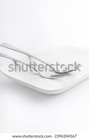 Spoon and fork on white plate on white background, High Key Photography