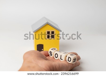 Close-up of House model with sold sign in hand, isolated on white background