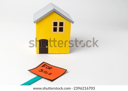 For Sale sign board in front of a  blue and yellow model home, isolated on white background