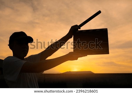 Teenage boy holding a film slate or film clapper board at sunset. new content creator, young filmmaker.
