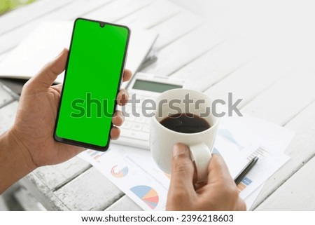 Businessmen use an empty smartphone at the coffee shop. His Hands are holding the smartphone with a green screen. For the creators to put in additional images. Financial development, Banking Account, 
