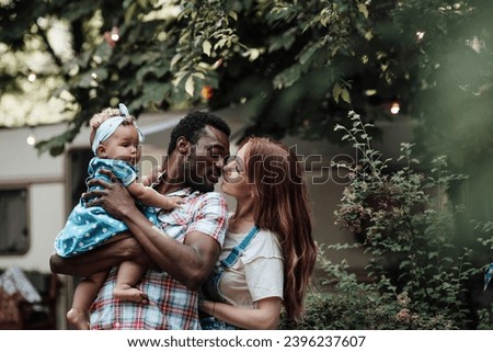 Mixed race family with dark skinned infant daughter spend time together hugs and kisses in camper park. African american man his fair skin wife and little girl enjoying summer vacation in open air