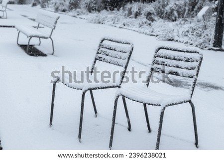 Saint Gallen, Switzerland, November 28, 2023 Fresh snow is falling on chairs at the botanical garden