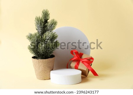 Bright gift and tree near a white podium with copy space. Christmas or New Year celebration concept