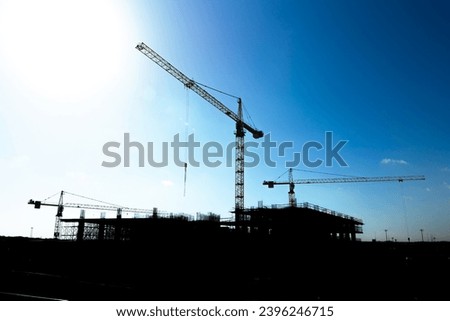Silhouette of a construction site with tower cranes and under constructed building. Development or civil engineering or architecture or business concept background photo.