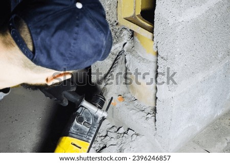 Hammer drill work background. Construction site job. Chimney installation. Young worker using power tools. Home renovation. Concrete block construction.
