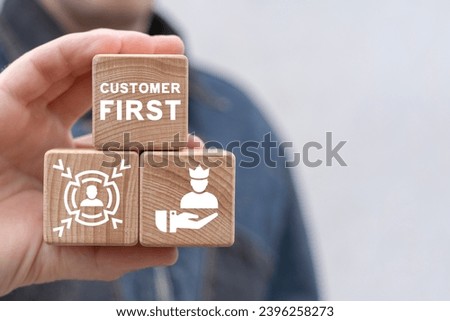 Man holding wooden blocks with icon sees inscription: CUSTOMER FIRST. Client centricity business orientation. Customer first concept. VIP client servcie. Customer relationship management (CRM). Royalty-Free Stock Photo #2396258273