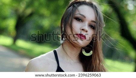Portraif of pretty hispanic girl looking to camera in outdoor park